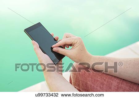 Using mobile phone by the swimming pool View Large Photo Image Stock Image - Using mobile phone by the swimming pool. Fotosearch