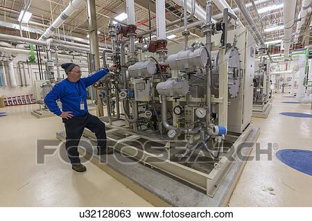 Stock Image - Water department engineer standing in chemical treatment room.. Fotosearch