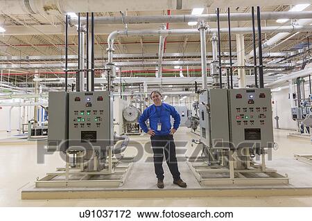 Stock Image - Water department engineer standing in chemical treatment room.. Fotosearch