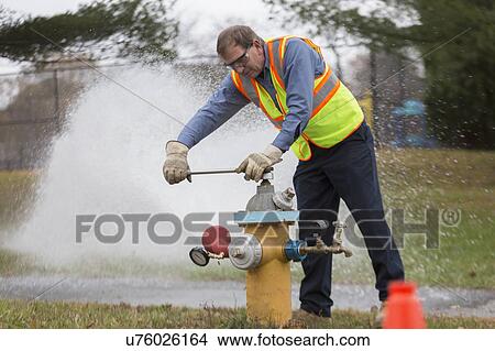 Picture - Water department technician opening fire hydrant to flush water pipes.. Fotosearch