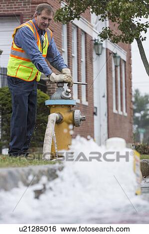 Water department technician opening fire hydrant to flush water mains. View Large Photo Image Stock Photograph - Water department technician opening fire hydrant to flush water mains.. Fotosearch