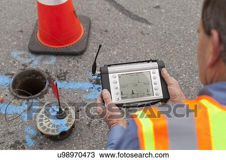 Stock Image - Water department technician reading a flow sensor.. Fotosearch