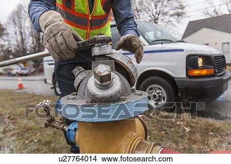 Picture - Water department technician shutting fire hydrant to flush water pipes.. Fotosearch