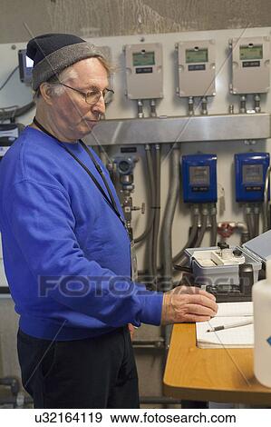 Stock Photo - Water treatment engineer recording data.. Fotosearch