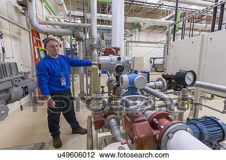 Stock Image - Water treatment plant engineer inspecting chemical treatment equipment.. Fotosearch
