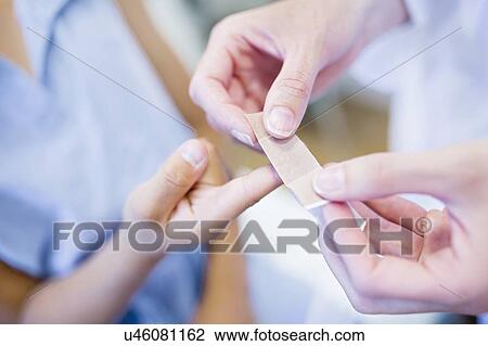 Woman applying plaster to girl's finger. View Large Photo Image Stock Image - Woman applying plaster to girl's finger.. Fotosearch