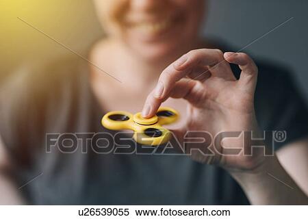 Stock Photography - Woman playing with fidget spinner. Fotosearch