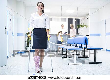 Stock Photo - Woman walking with crutches in medical waiting room.. Fotosearch