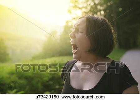 Stock Image - Woman yawning outdoors. Fotosearch