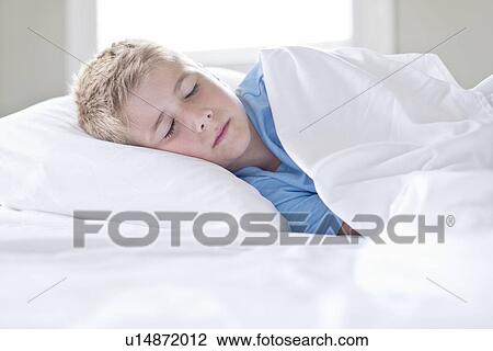 Stock Image - Young boy asleep with head on pillow.. Fotosearch