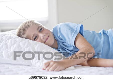 Young boy lying with head on pillow, smiling. View Large Photo Image Stock Image - Young boy lying with head on pillow, smiling.. Fotosearch
