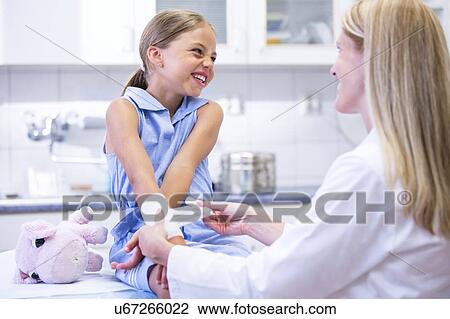 Stock Image - Young girl having bandage applied to arm.. Fotosearch