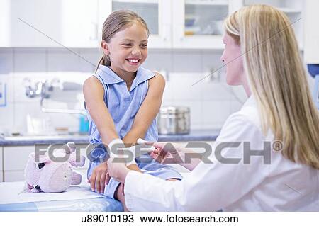 Stock Image - Young girl having bandage applied to arm.. Fotosearch