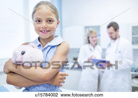 Young girl in doctor's room hugging teddy, smiling. View Large Photo Image Stock Image - Young girl in doctor's room hugging teddy, smiling.. Fotosearch