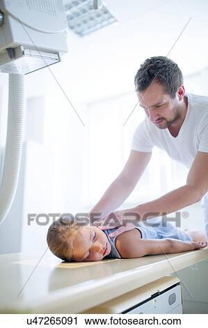 Young girl lying face down in hospital with radiologist positioning her for X-ray. View Large Photo Image Stock Image - Young girl lying face down in hospital with radiologist positioning her for X-ray.. Fotosearch