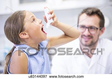 Stock Photo - Young girl using inhaler with doctor watching.. Fotosearch