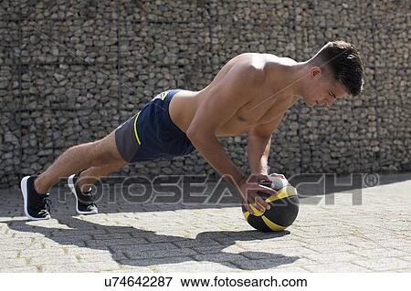 Young man balancing on medicine ball, doing push-up. View Large Photo Image Stock Photo - Young man balancing on medicine ball, doing push-up.. Fotosearch