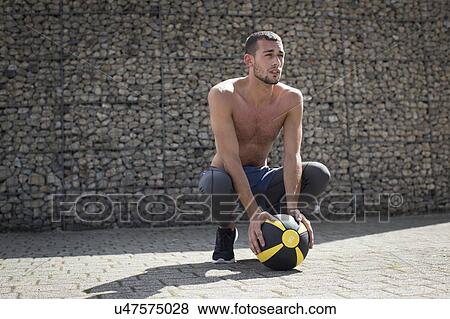 Young man crouching with medicine ball. View Large Photo Image Stock Photo - Young man crouching with medicine ball.. Fotosearch