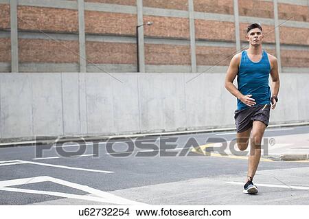 Picture - Young man running on road.. Fotosearch