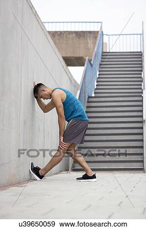 Young man stretching leg against wall. View Large Photo Image Stock Photo - Young man stretching leg against wall.. Fotosearch