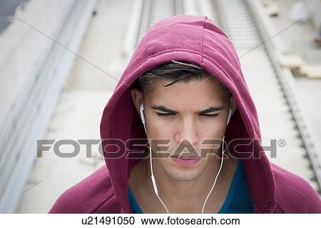 Young man wearing ear phones and hooded top. View Large Photo Image Stock Image - Young man wearing ear phones and hooded top.. Fotosearch