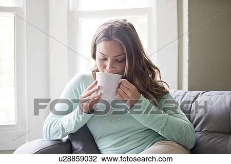 Young woman drinking hot drink from a mug. View Large Photo Image Stock Image - Young woman drinking hot drink from a mug.. Fotosearch