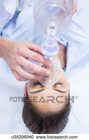 Stock Image - Young woman with resuscitation mask covering mouth.. Fotosearch