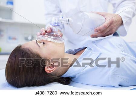 Stock Image - Young woman with resuscitation mask covering mouth.. Fotosearch