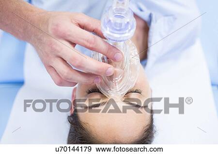Stock Photo - Young woman with resuscitation mask covering mouth.. Fotosearch
