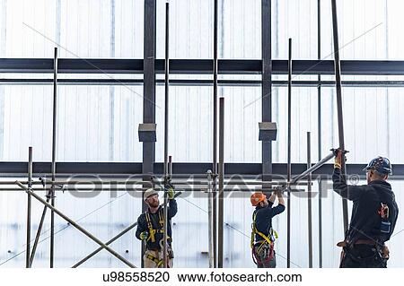 Stock Image - Apprentice engineers preparing and setting up scaffolding. Fotosearch