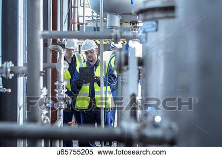 Stock Photography - Apprentice engineers working on pipeline in industrial product facility. Fotosearch
