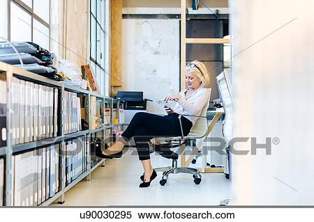 Stock Photography - Architect reading by filing shelves. Fotosearch