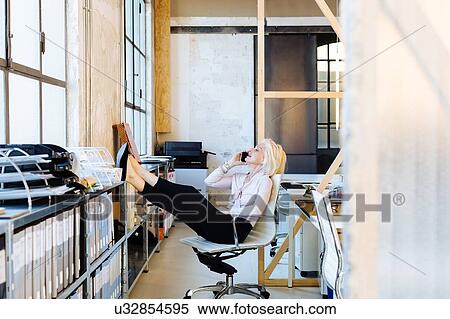 Architect using mobile phone with legs propped up View Large Photo Image Stock Photography - Architect using mobile phone with legs propped up. Fotosearch