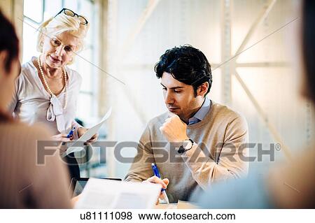 Stock Photo - Architects going through documents together. Fotosearch
