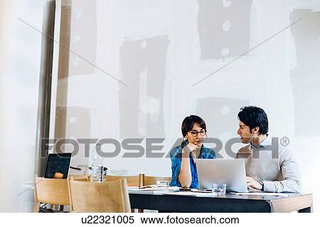 Stock Photography - Architects having discussion at laptop. Fotosearch
