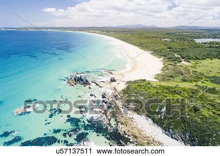 Stock Image - Australia, New South Wales, Bermagui, Landscape with forest and beach. Fotosearch