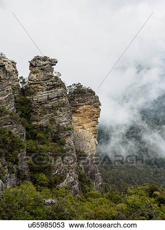 Stock Image - Australia, New South Wales, Katoomba, Large rocks and mountains in clouds. Fotosearch