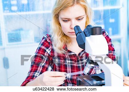 Stock Photo - Biology lesson. Student using a light microscope.. Fotosearch