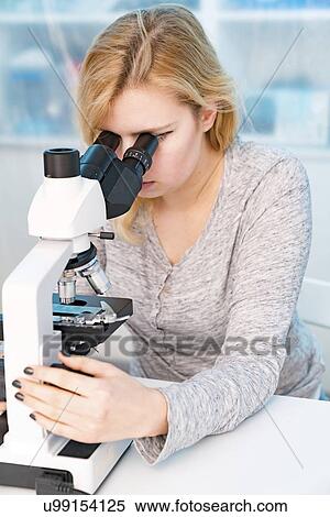 Stock Photography - Biology lesson. Student using a light microscope.. Fotosearch