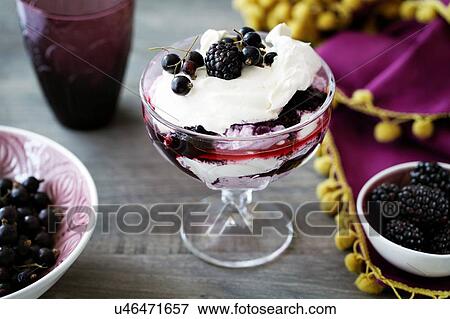 Stock Photo - Blackberry fool with cream in dessert glass, close-up. Fotosearch