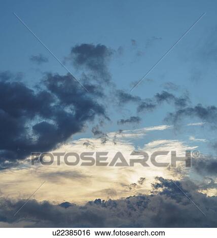 Stock Photograph - Blue sky with storm clouds at sunset. Fotosearch