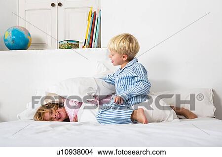 Boy and female twin play fighting on bed View Large Photo Image Picture - Boy and female twin play fighting on bed. Fotosearch
