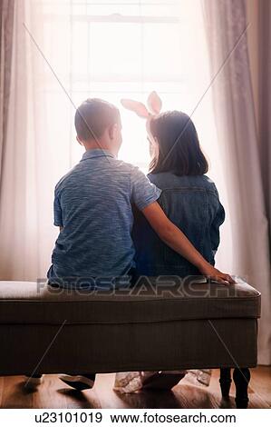 Boy and girl, sitting in front of window, girl wearing bunny ears, rear view View Large Photo Image Stock Photo - Boy and girl, sitting in front of window, girl wearing bunny ears, rear view. Fotosearch