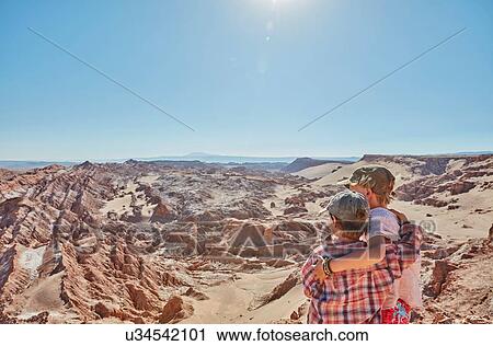 Stock Image - Boy and his brother looking out over desert landscape, Atacama, Chile. Fotosearch
