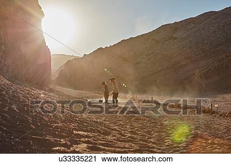 Stock Image - Boy and his brother pulling toy trucks along desert path, Atacama, Chile. Fotosearch