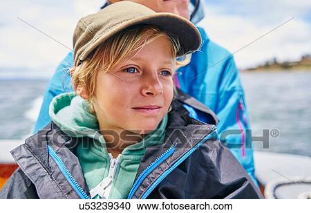 Stock Image - Boy and his mother on motor boat at sea, Puno, Peru. Fotosearch