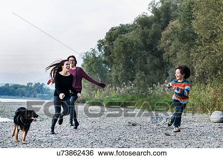 Boy and young women running with dog along riverside, Calolziocorte, Lombardy, Italy View Large Photo Image Stock Photograph - Boy and young women running with dog along riverside, Calolziocorte, Lombardy, Italy. Fotosearch