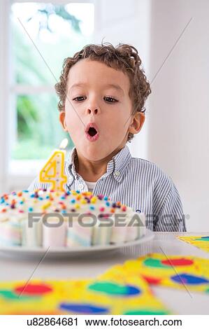 Stock Image - Boy blowing out candles on birthday cake. Fotosearch