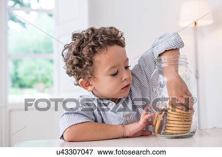 Boy getting biscuit from cookie jar View Large Photo Image Stock Photo - Boy getting biscuit from cookie jar. Fotosearch