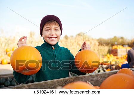 Boy holding harvested pumpkins in field View Large Photo Image Stock Image - Boy holding harvested pumpkins in field. Fotosearch